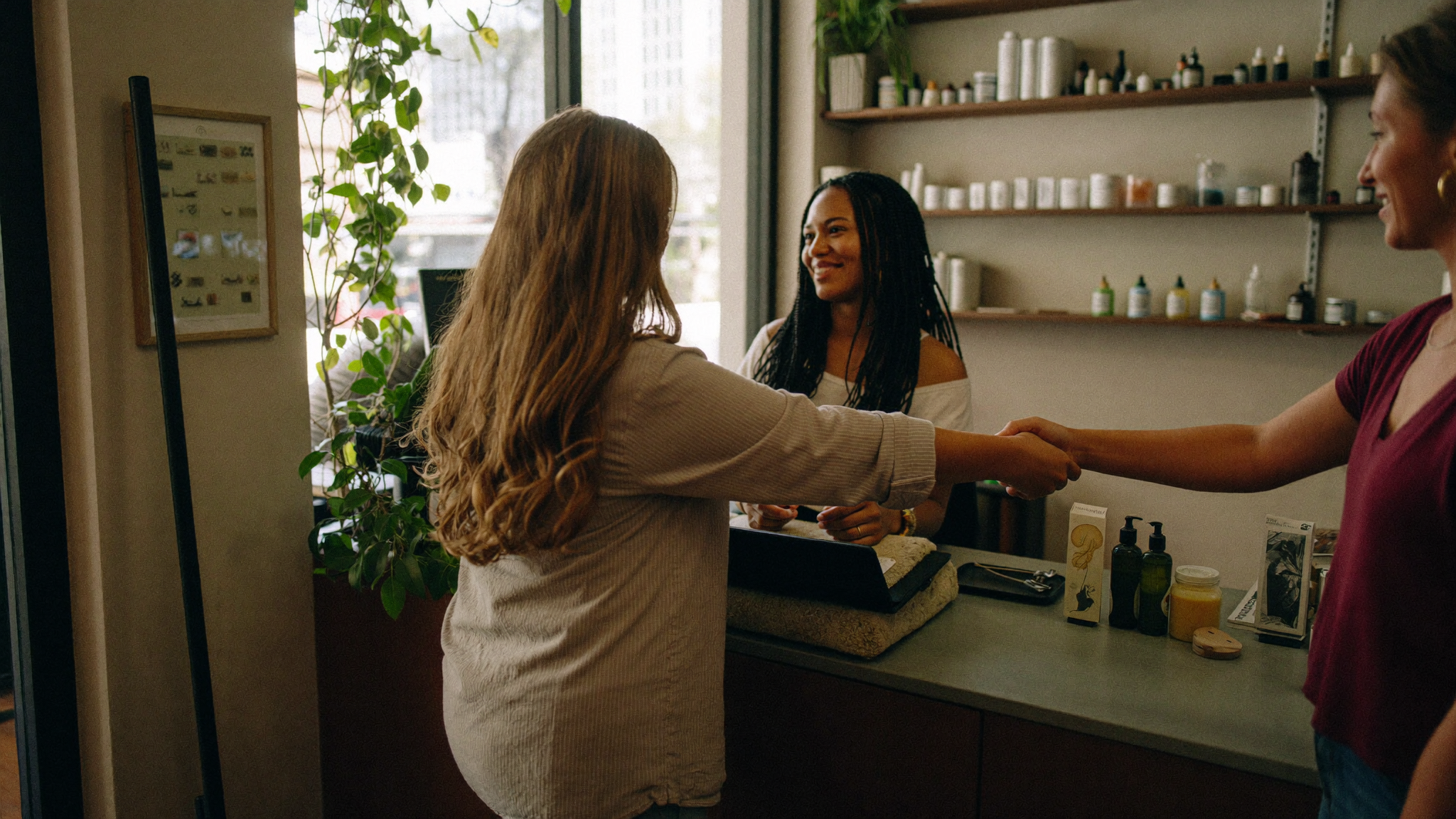 Studio owner greeting a returning client at the front desk